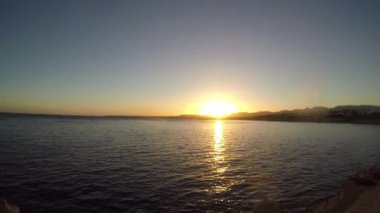Günbatımı denize. Ufukta kıyı şeridi görebilirsiniz