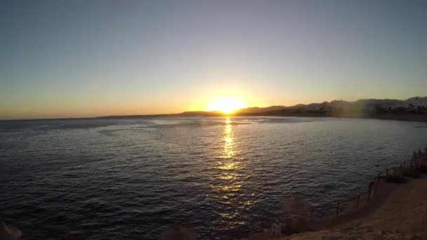 Человек на пляже смотрит на закат — стоковое видео