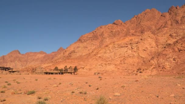 Сільські будівлі біля підніжжя пустельних гір — стокове відео
