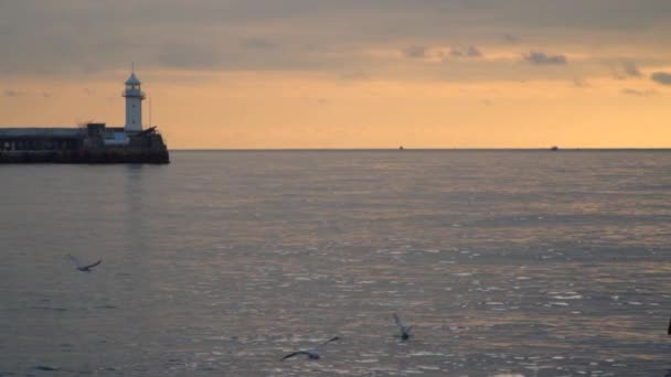 Phare à la jetée contre le ciel au coucher du soleil 