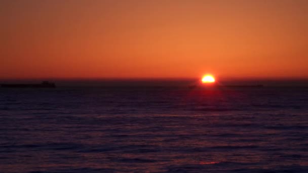 Схід сонця над морем. На горизонті видно вантажні кораблі — стокове відео