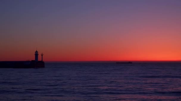 Un muelle con un faro intermitente al amanecer — Vídeos de Stock