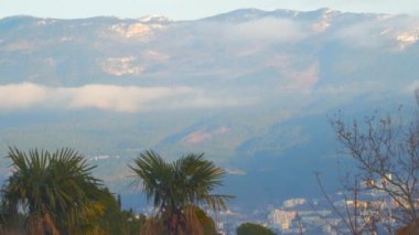 Bulutlarda karla kaplı dağların eteklerindeki şehir