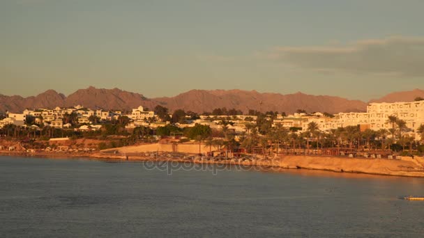 Edifici sullo sfondo delle montagne desertiche sulla spiaggia — Video Stock