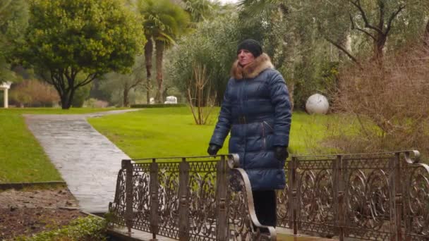 Een vrouw in de regen op een bruggetje — Stockvideo