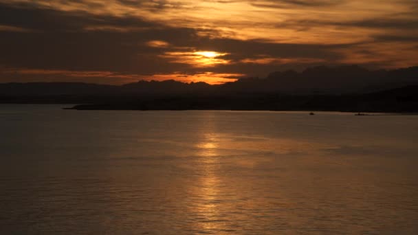 Siluetter av berg på kusten mot himlen vid solnedgången — Stockvideo