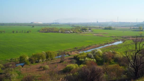 Vue de la colline sur le Champ et la rivière. À l'horizon, vous pouvez voir la plante et la fumée de la plante 