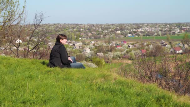 Μια Νεαρή Γυναίκα Κάθεται Πάνω Ένα Λόφο Και Κοιτάζει Προς — Αρχείο Βίντεο