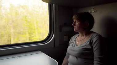Trendeki bir kadın pencereden dışarı bakıyor. Hareket halindeki tren