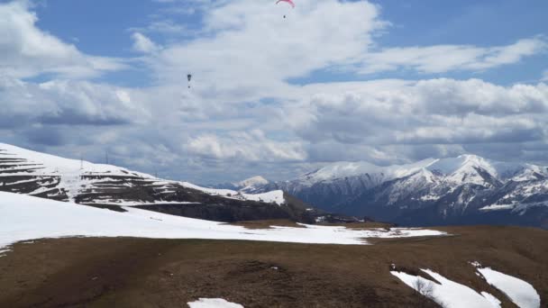 Парапланеристы Летают Среди Заснеженных Гор Кавказские Горы — стоковое видео