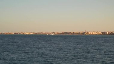 Akşamları Panaroma kıyısı. Mısır 'daki Kızıldeniz kıyılarında rüzgar türbinleri ve binalar. Gemiden görüntüle