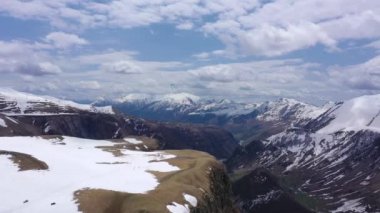 Paraglider karlı dağların üzerinden uçar. Kafkasların dağları. İnsansız hava aracı ile video görüntüsü