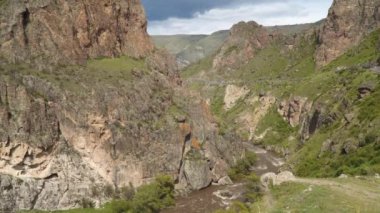 Bulutlu gökyüzüne karşı Rocky Dağları. Kanyonun dibindeki nehri görebilirsin.