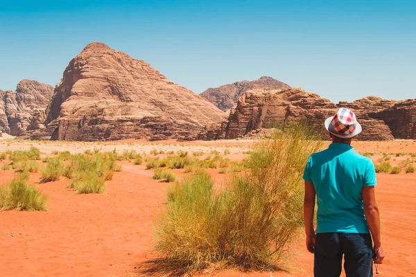 Elegante hombre con sombrero de moda y camiseta mirando un paisaje increíble disfrutando de la vida. Viajero, viajes de libertad, vacaciones de lujo, concepto de vida activa . —  Fotos de Stock