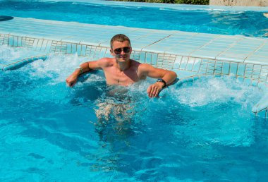 Kendine güvenen başarılı adam havuzunda rahatlatıcı spa açık Jakuzi tesisi lüks hayatın tadını. Başarı, sağlıklı yaşam, vücut bakım kavramı.