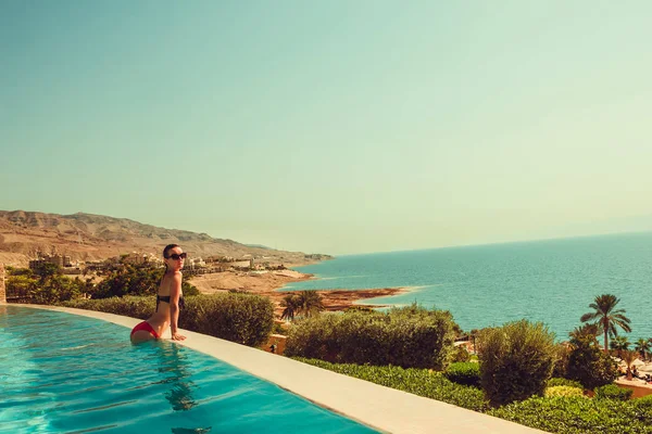 Сексуальная модель, отдыхающая в бассейне "Бесконечность". Молодая женщина отдыхает на курорте. Летний роскошный отпуск. Концепция туризма и путешествий. Наслаждаюсь загаром. Мертвое море, Джордан. Освежение . — стоковое фото
