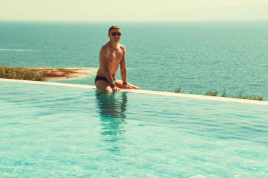 Başarılı zengin sonsuzluk havuzunda rahatlatıcı adamım ve iyi tatiller. Spa resort. Lüks bir yaşam tarzı. Vücut bakım kavramı. Ölü Deniz Manzaralı. Zengin insanlar. Turizm ve seyahat. Uzay kopyalayın. Serbest zaman.