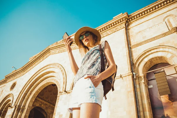 Mulher turista de chapéu com mochila usando navegação GPS no telefone móvel. Estilo de moda de verão. Excursão. Explore o mundo. Tecnologia moderna. Conceito de turismo. Yerevan. Vista inferior. Internet sem fios . — Fotografia de Stock