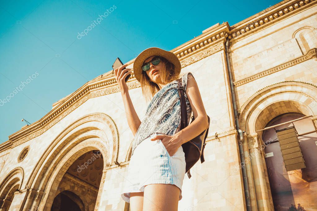 Woman tourist in hat with backpack using gps navigation on mobile phone. Summer fashion style. City tour. Explore world. Modern technology. Tourism concept. Yerevan. Bottom view. Wireless internet.
