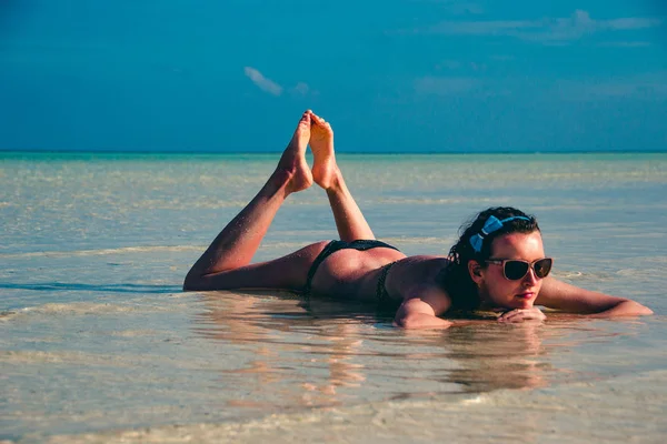 Young woman lying in water. Girl sunbathing in bikini and relax, enjoying life, lifestyle. Exotic tropical beach. Summer vacation resort and tourism, luxury travel concept. Paradise holiday island — Stock Photo, Image