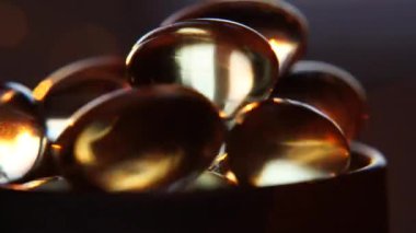 Omega 3 altın balık yağı kapsülleri, dönüşümlü arka plan, makro. Altın kapsül yağ takviyesi dönüşümlü hareket