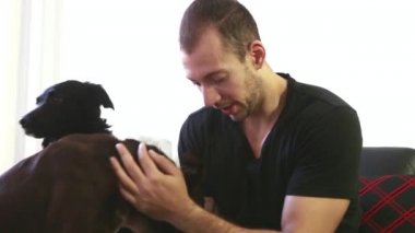 Genç adam peting köpekler süre kanepede kahve içme