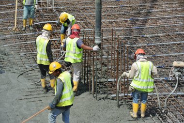 Bir grup inşaat işçileri beton zemin döşeme formu çalışma içine dökme