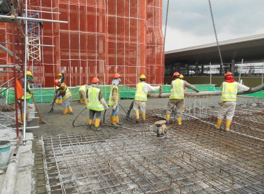 Bir grup inşaat işçileri beton zemin döşeme formu çalışma içine dökme