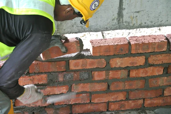 Pekerja konstruksi meletakkan batu bata di lokasi konstruksi — Stok Foto