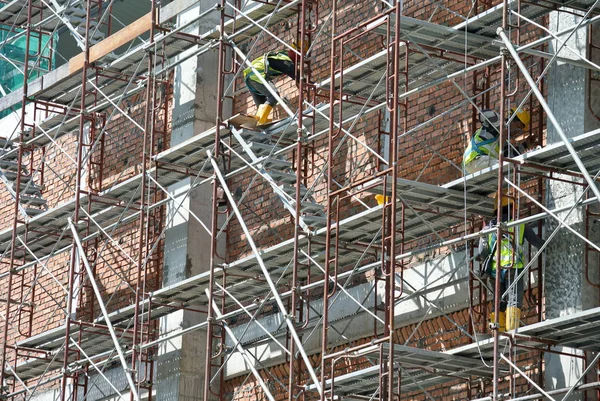 Pracowników budowlanych na sobie uprząż bezpieczeństwa i Instalowanie rusztowania — Zdjęcie stockowe