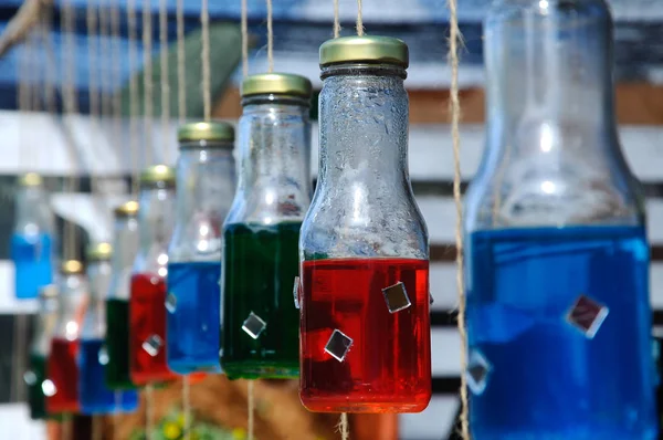  Asılı ve renkli su dolu cam şişeler.