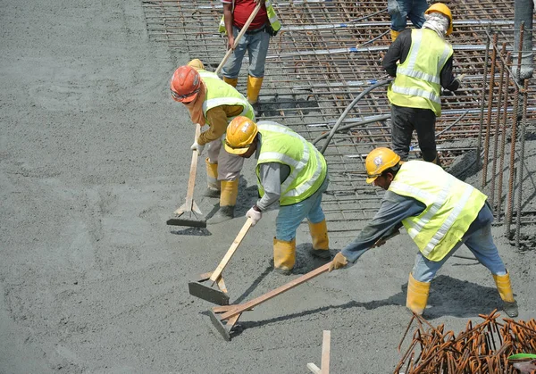 Bouwvakkers herverdeling van natte beton heeft zijn gegoten. — Stockfoto
