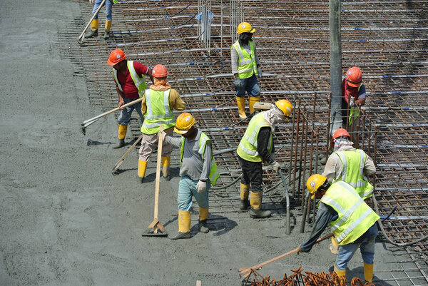  Construction workers leveling wet concrete has been poured. 
