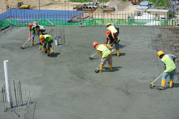  Construction workers leveling wet concrete has been poured. 