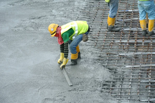 Bouwvakkers herverdeling van natte beton heeft zijn gegoten. — Stockfoto