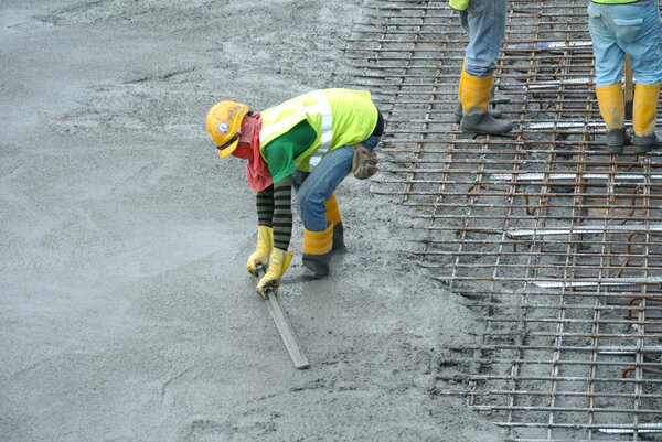  Construction workers leveling wet concrete has been poured. 