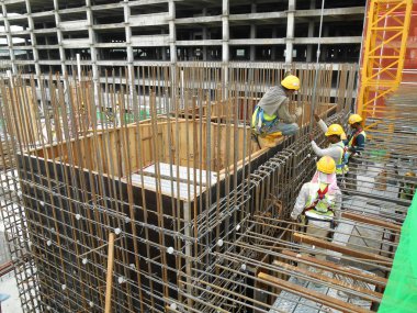 İnşaat işçileri inşaat alanında çelik takviye çubuğu üretiyorlar.