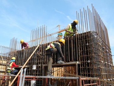 İnşaat işçileri inşaat alanında çelik takviye çubuğu üretiyorlar.