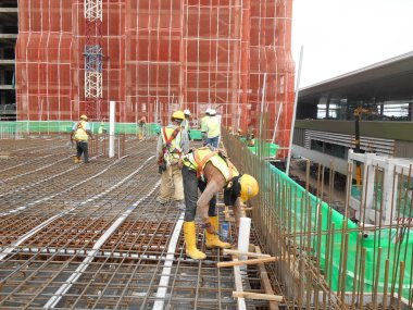 İnşaat işçileri inşaat alanında çelik takviye çubuğu üretiyorlar.