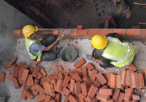 Trabalhador ricklayer colocar tijolos de argila vermelha para formar paredes de construção — Fotografia de Stock