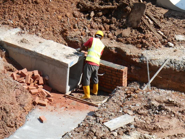 Trabajadores de la construcción instalan drenaje de alcantarilla de caja de hormigón prefabricado subterráneo — Foto de Stock