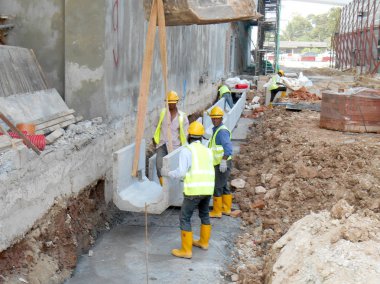 İnşaat İşçileri prekast u şeklinde beton drenaj inşaat sahasında yükleme.