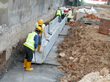 İnşaat İşçileri prekast u şeklinde beton drenaj inşaat sahasında yükleme.