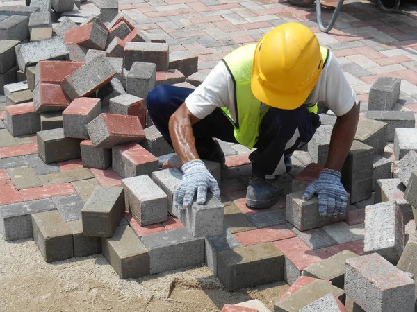 Trabajadores de la construcción instalando y arreglando adoquines de hormigón prefabricados de piedra —  Fotos de Stock
