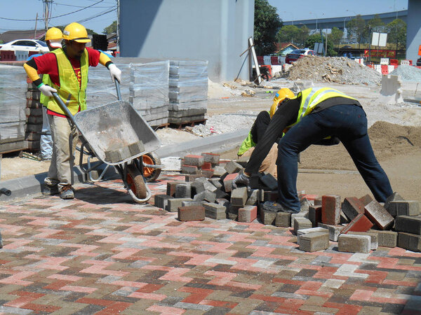 Construction workers installing  and arranging precast concrete pavers stone