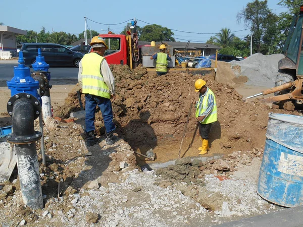 Construction workers install underground utility and services pipe. — Stock Photo, Image