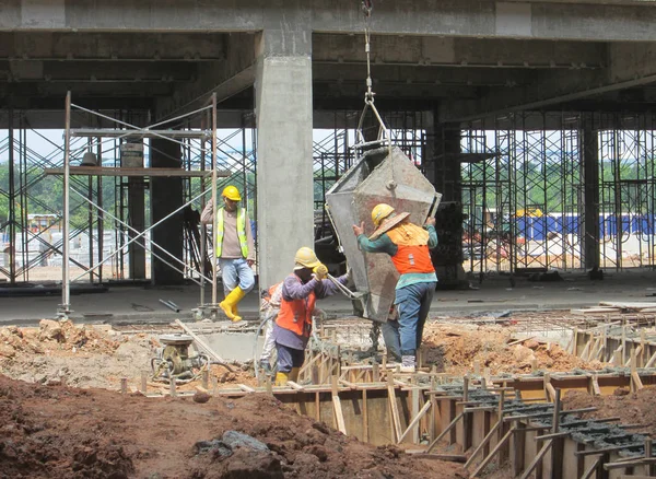 Construction workers pouring wet concrete using concrete bucket — Stock Photo, Image
