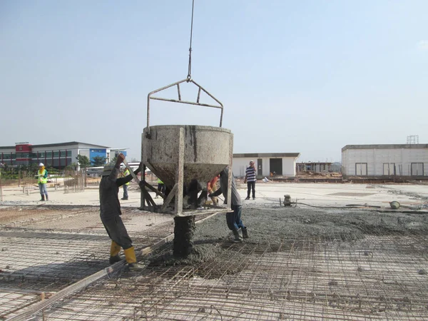 Trabajadores de la construcción vertiendo hormigón húmedo utilizando cubo de hormigón —  Fotos de Stock