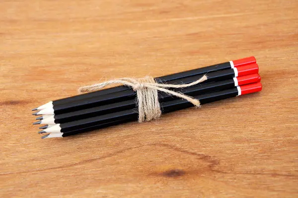 Black pencils tied with a rope of straw yarn. — Stock Photo, Image