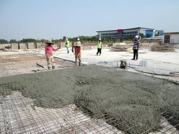 Construction workers leveling  wet concrete